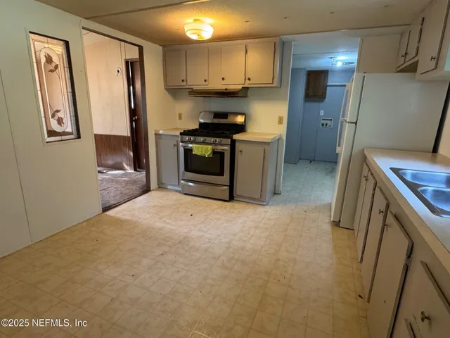 a kitchen with stainless steel appliances granite countertop a refrigerator a stove and a sink