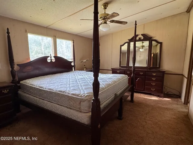 a bedroom with a bed a dresser and window