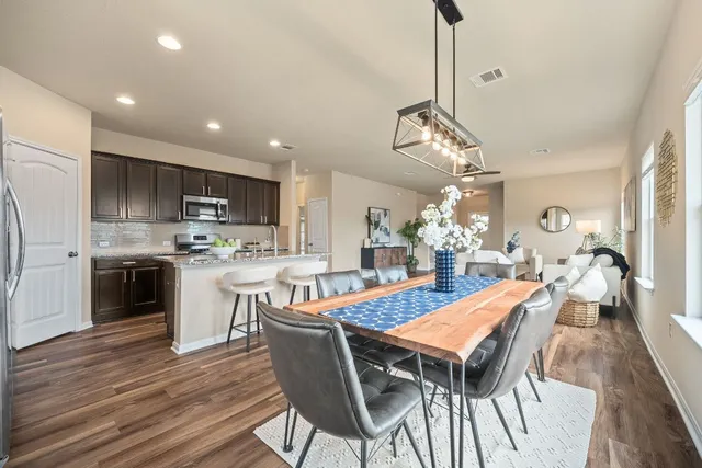 a dining room filled chandelier and wooden floor