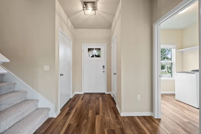 a view of a hallway with wooden floor and staircase
