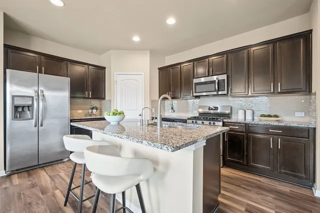 a kitchen with kitchen island granite countertop a sink stove and refrigerator