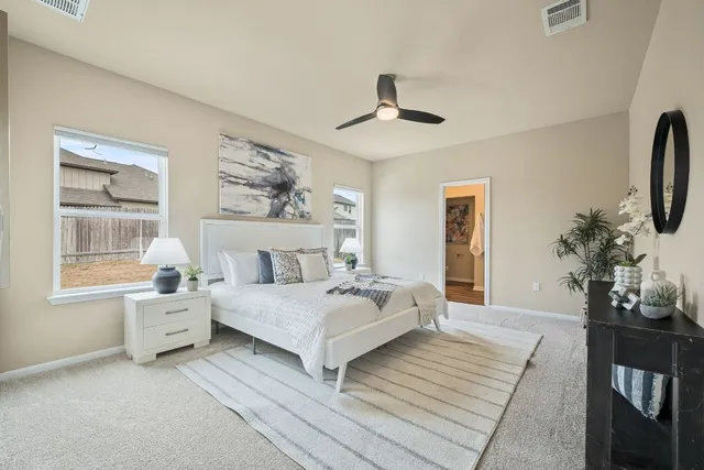 a spacious bedroom with a large bed a chandelier and windows