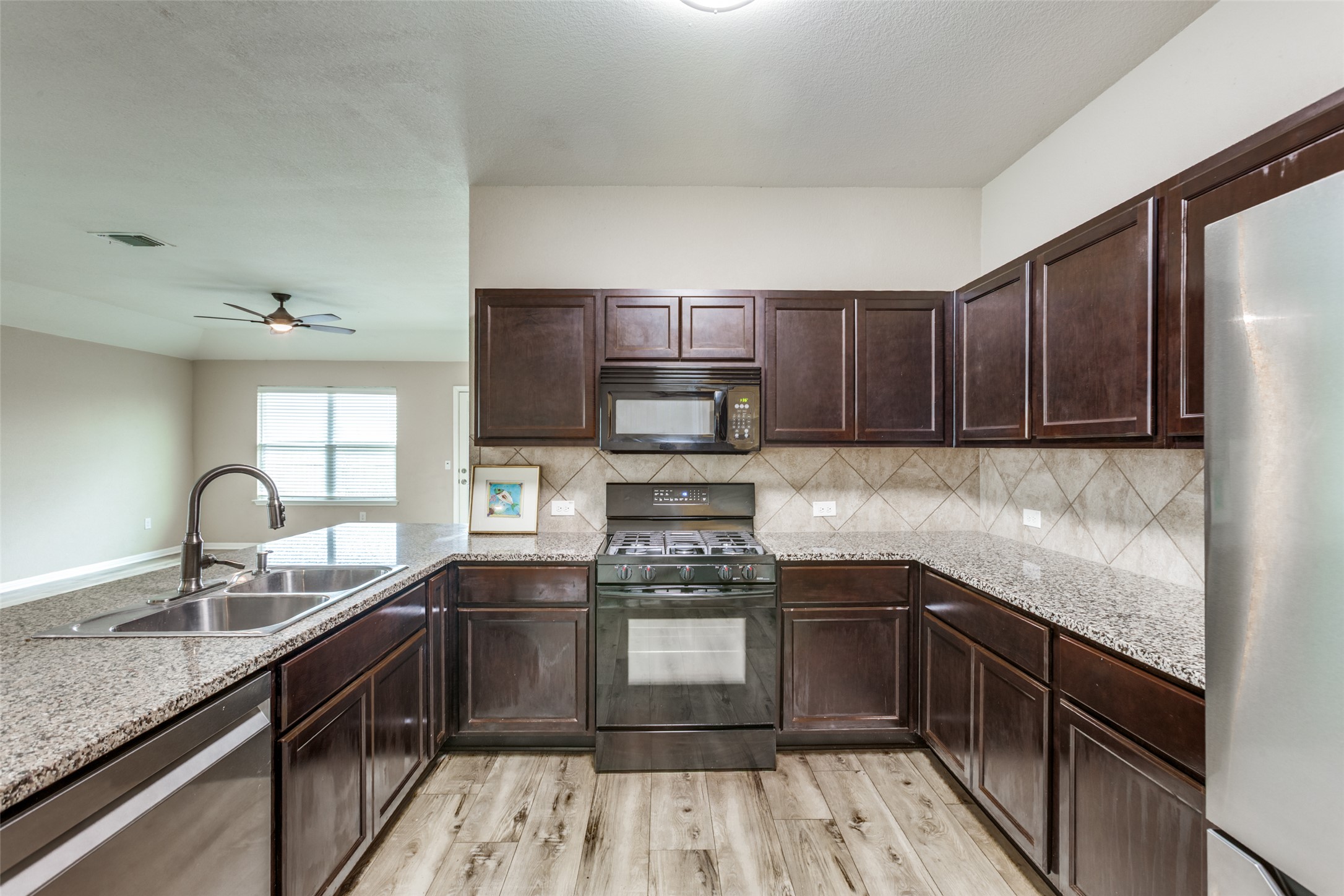 2909 Centrum Drive Austin, TX 78754 - Photo 16 of 30 This kitchen features dark wood cabinetry, granite countertops, a gas range, and wood-look flooring