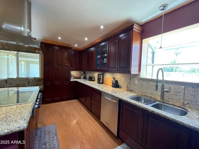 a kitchen with kitchen island granite countertop a sink stove and cabinets
