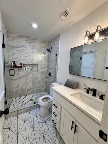 a bathroom with a granite countertop sink a toilet and a shower