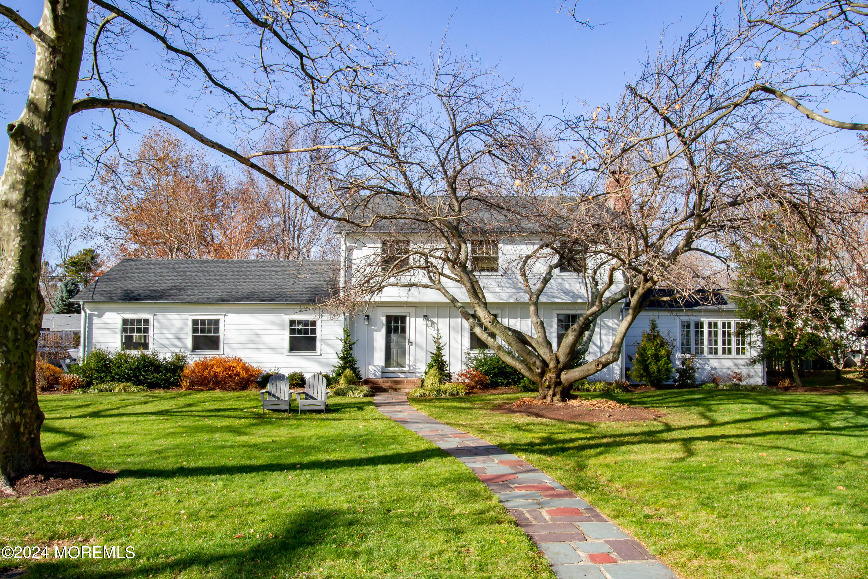 a front view of a house with garden and trees