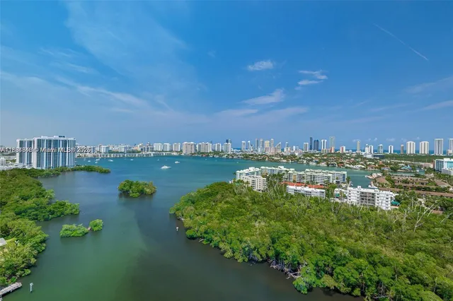 an aerial view of a city with lots of residential buildings ocean and mountain view in back