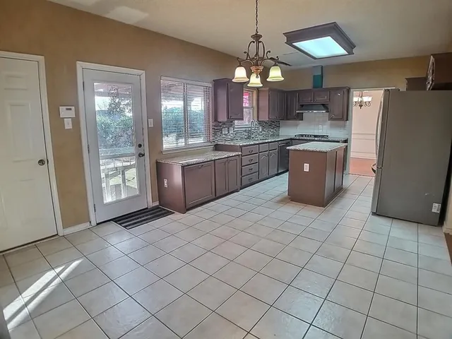 a large kitchen with a large counter top stainless steel appliances and cabinets