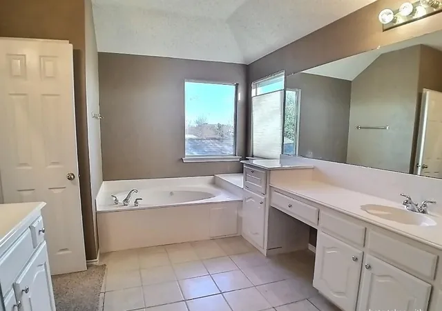 a spacious bathroom with a tub sink and mirror