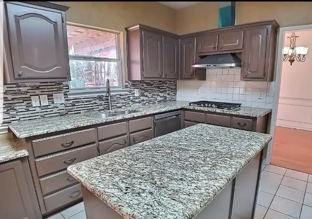 a kitchen with stainless steel appliances kitchen island granite countertop wooden cabinets a oven and granite counter tops