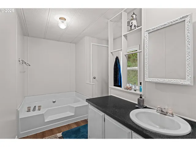 a bathroom with a granite countertop sink a mirror and a bathtub