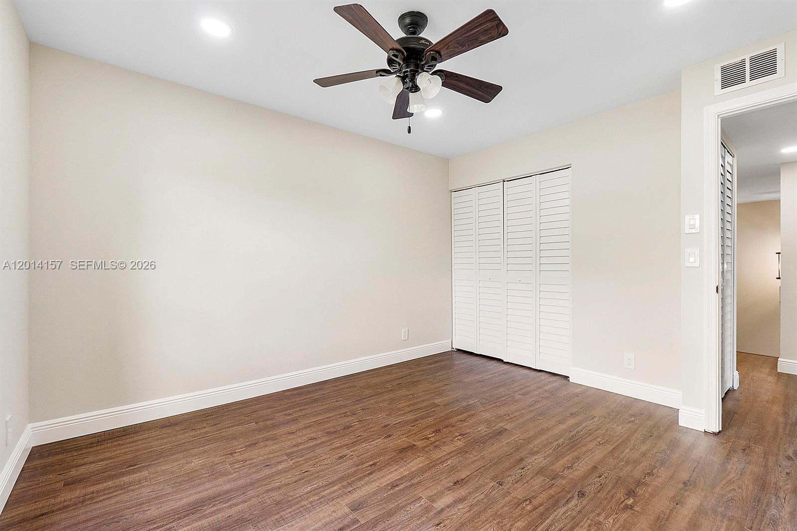 7744 Courtyard Run West Boca Raton, FL 33433 - Photo 11 of 25 an empty room with wooden floor and a ceiling fan