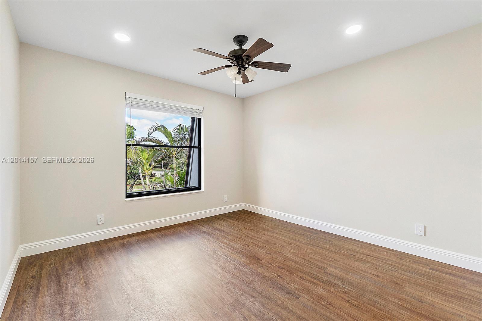 7744 Courtyard Run West Boca Raton, FL 33433 - Photo 12 of 25 an empty room with wooden floor chandelier fan and windows