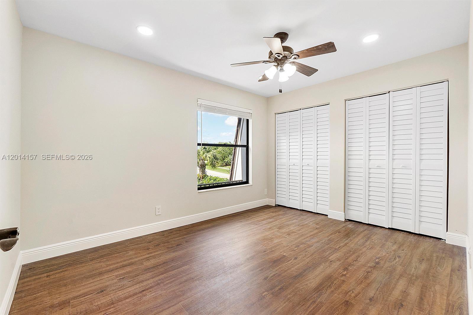 7744 Courtyard Run West Boca Raton, FL 33433 - Photo 13 of 25 an empty room with wooden floor chandelier fan and windows