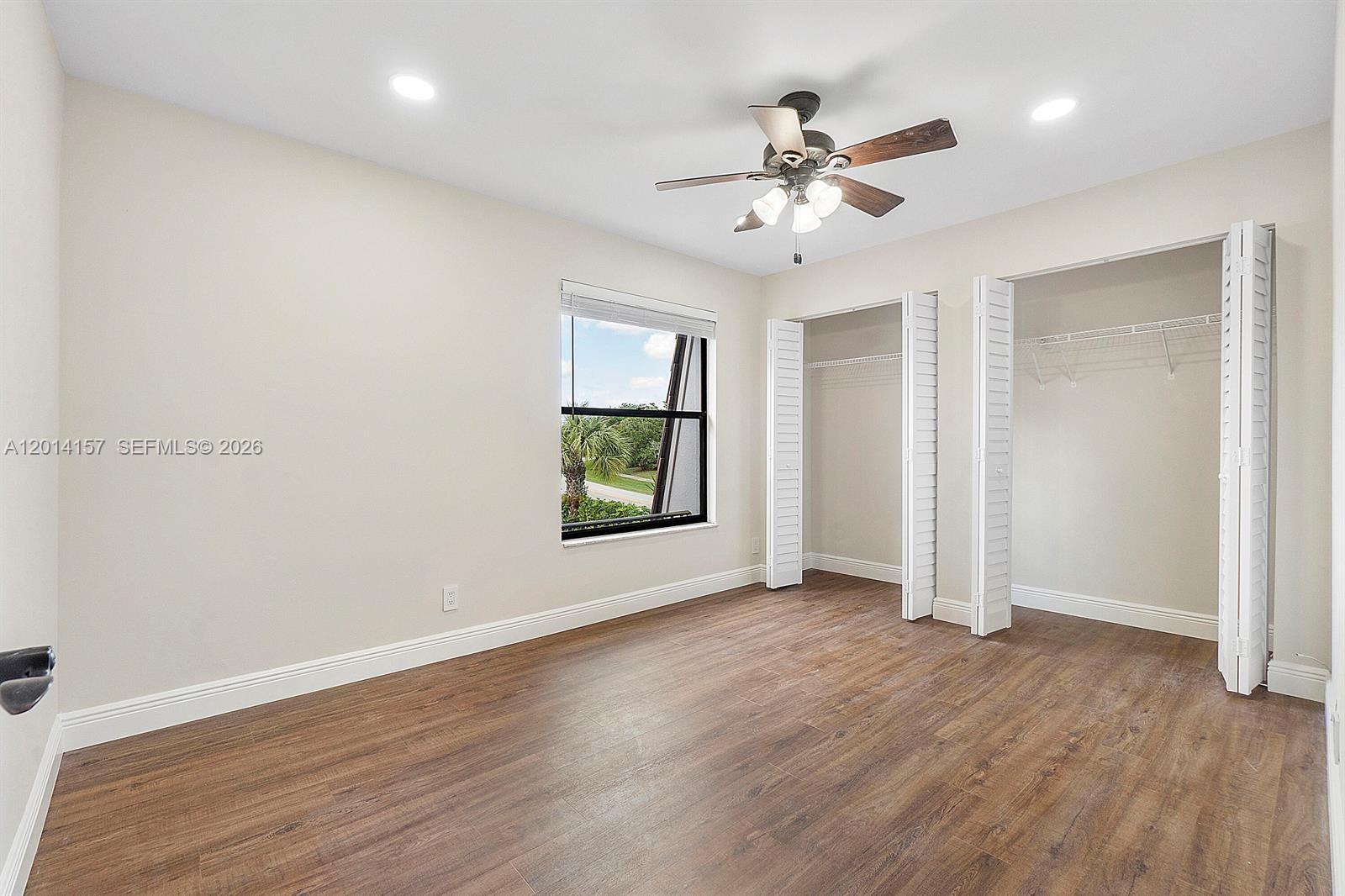 7744 Courtyard Run West Boca Raton, FL 33433 - Photo 14 of 25 an empty room with wooden floor chandelier fan and windows
