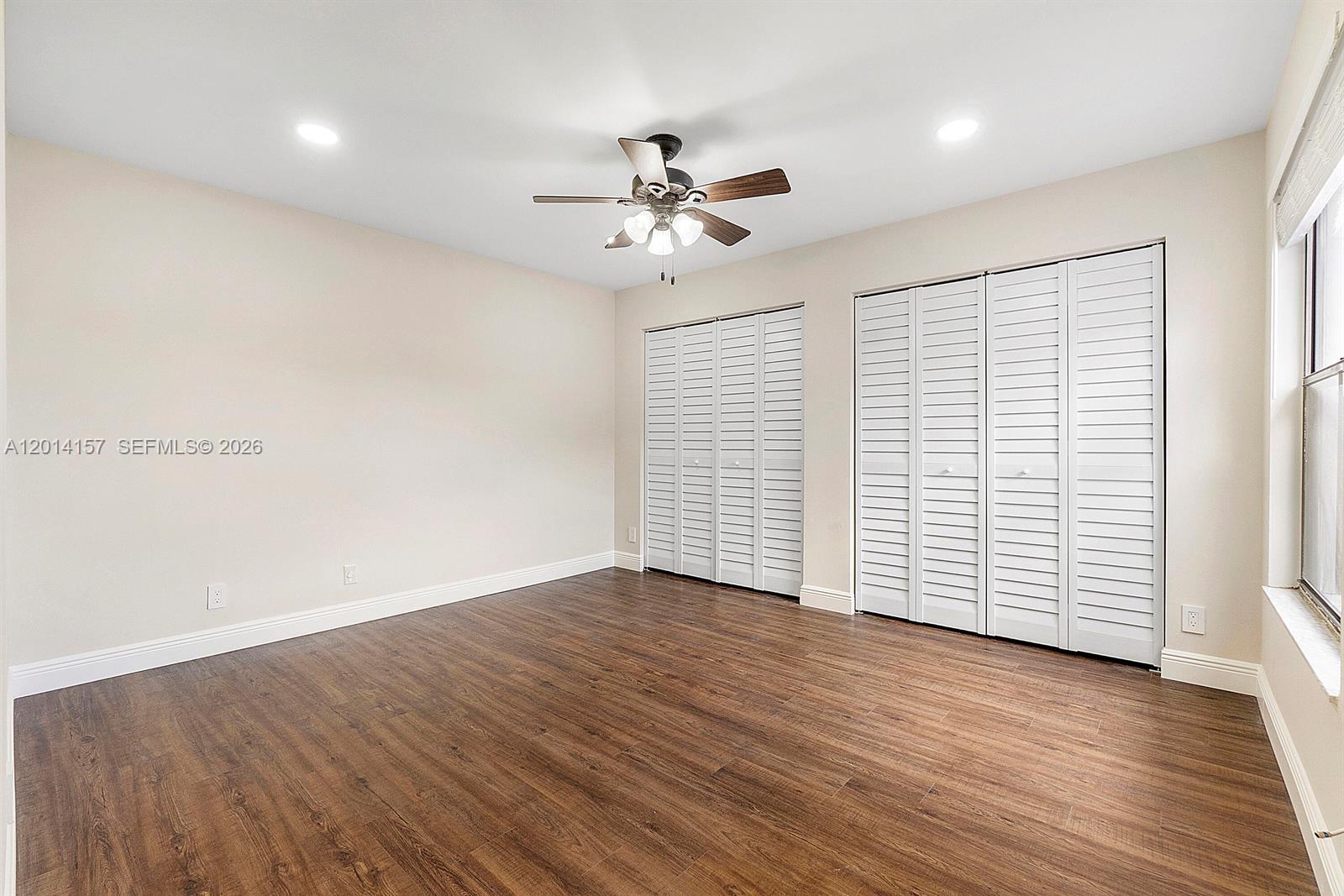 7744 Courtyard Run West Boca Raton, FL 33433 - Photo 15 of 25 an empty room with wooden floor chandelier fan and windows