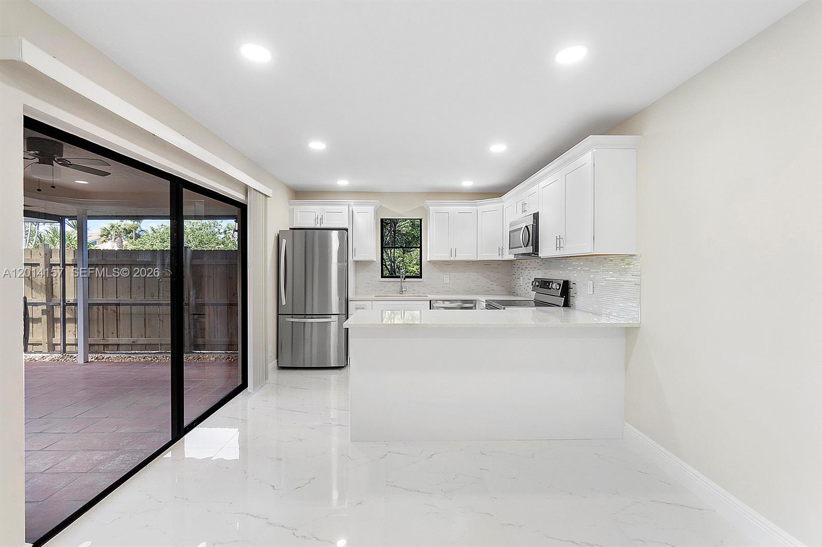 7744 Courtyard Run West Boca Raton, FL 33433 - Photo 2 of 25 a kitchen with stainless steel appliances granite countertop a refrigerator and a sink