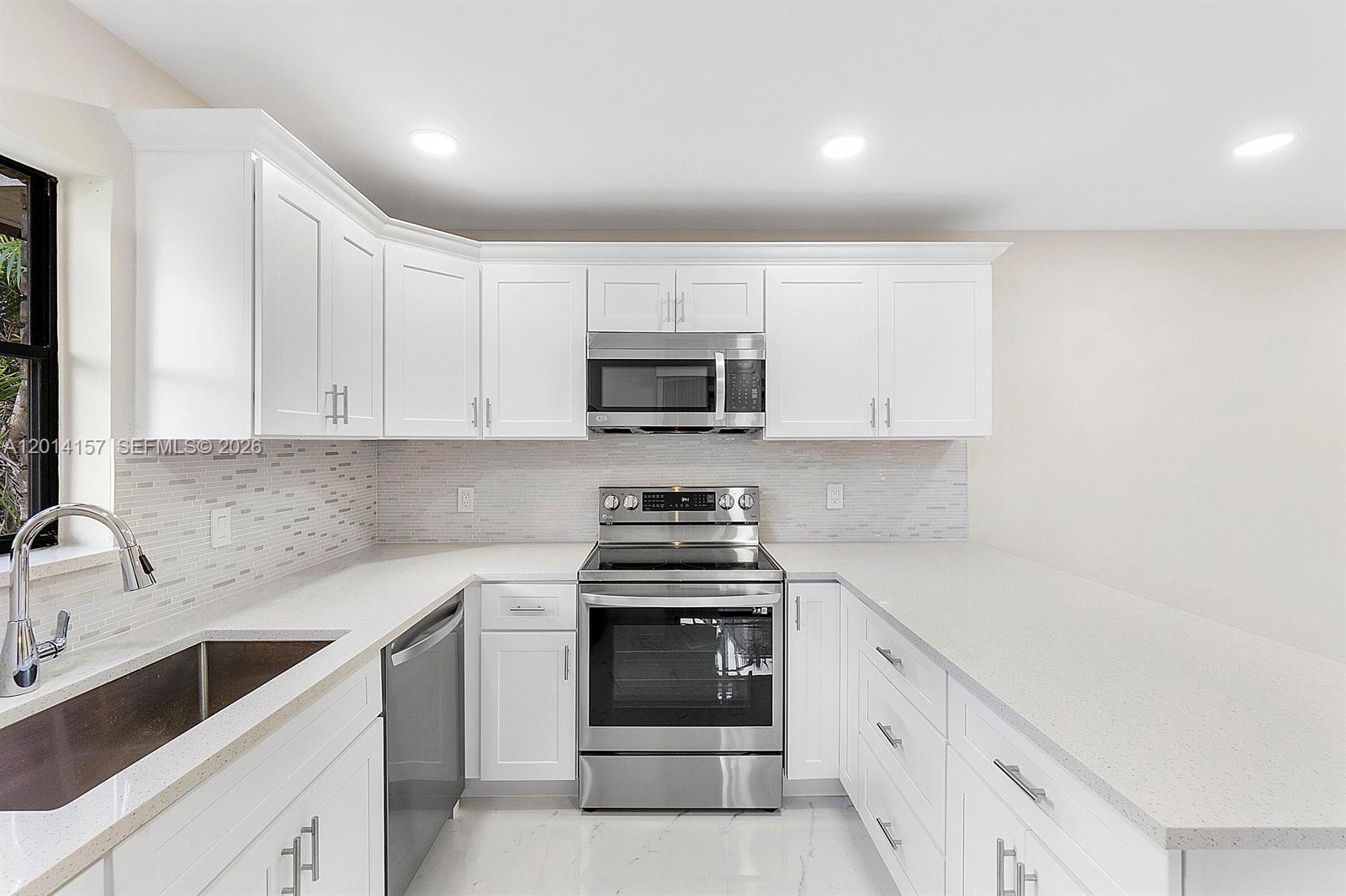7744 Courtyard Run West Boca Raton, FL 33433 - Photo 3 of 25 a kitchen with granite countertop white cabinets and stainless steel appliances