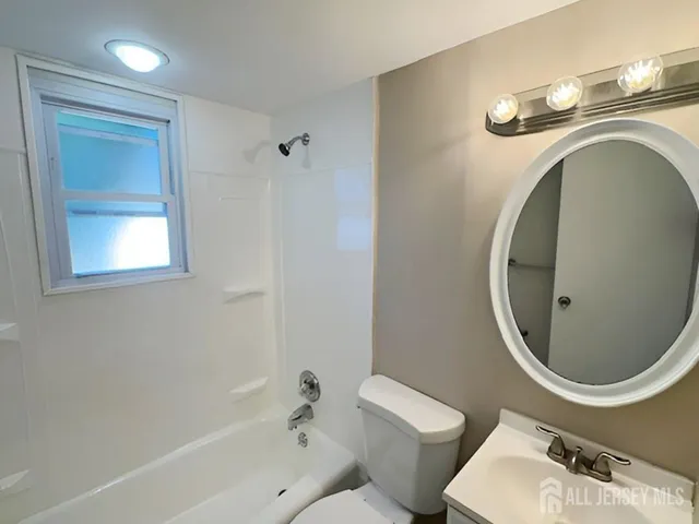 a bathroom with a toilet sink mirror and vanity