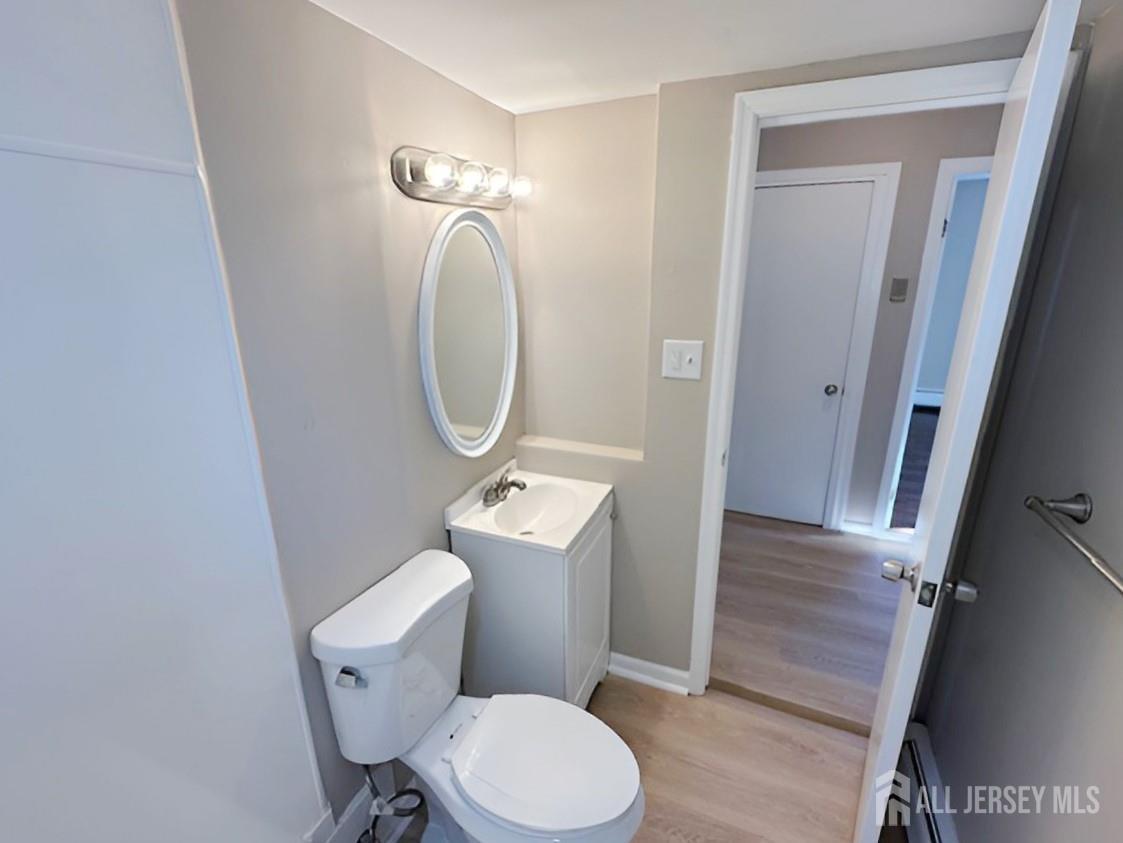 125 Raritan Boulevard Old Bridge, NJ 07735 - Photo 12 of 29 a bathroom with a toilet a sink a mirror and wooden floor