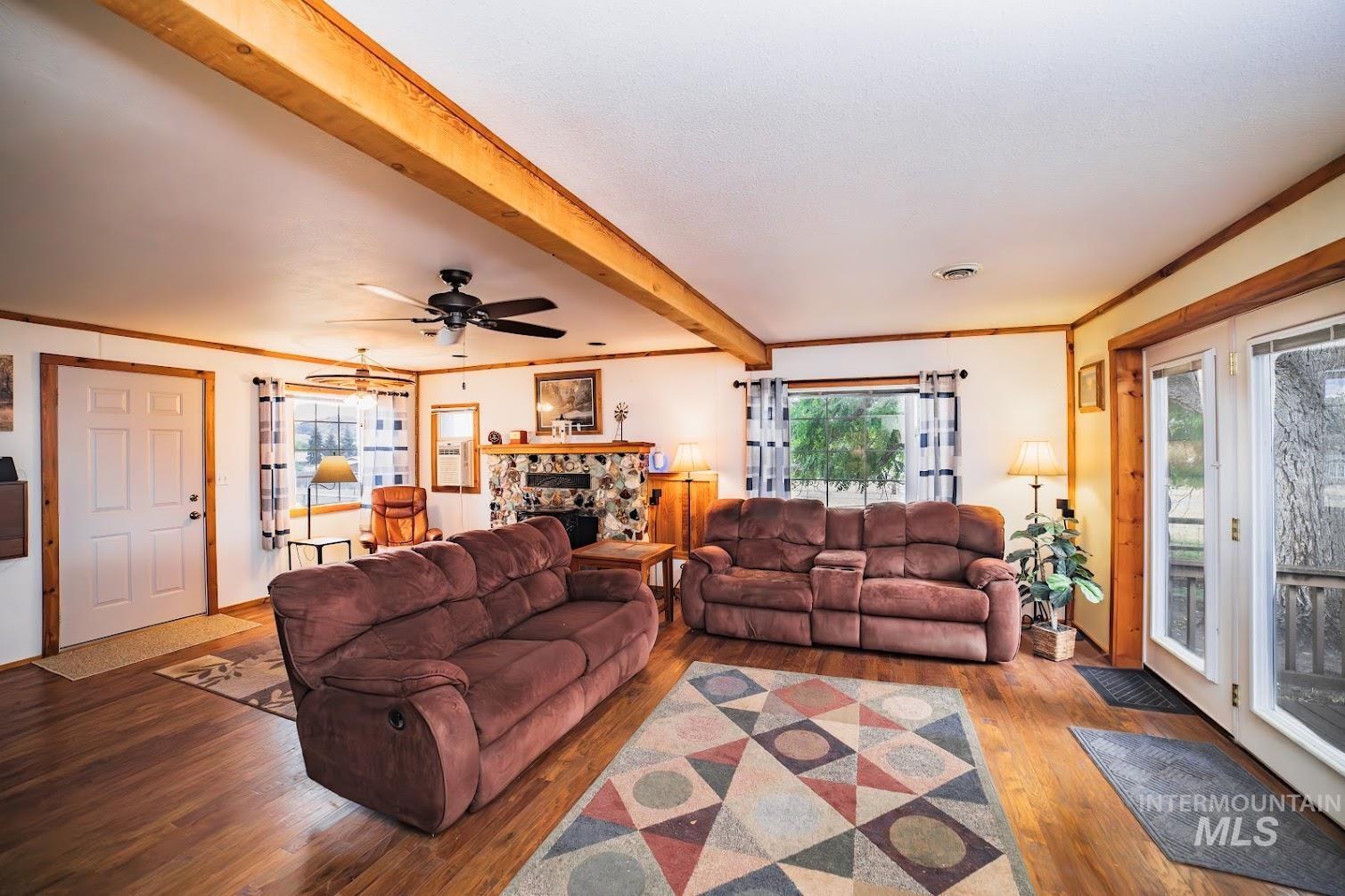 69431 Antles Road, Unit 1 Cove, OR 97824 - Photo 7 of 23 Living area with wood finished floors, ornamental molding, beamed ceiling, a fireplace, and a ceiling fan
