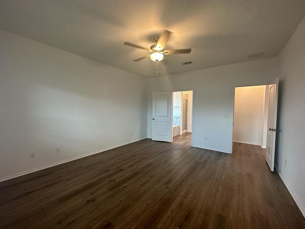 160 River Rise Road Kyle, TX 78640 - Photo 25 of 35 Spacious interior room featuring wood-finish flooring, light neutral wall tones, a ceiling fan with integrated lighting, and multiple entryways