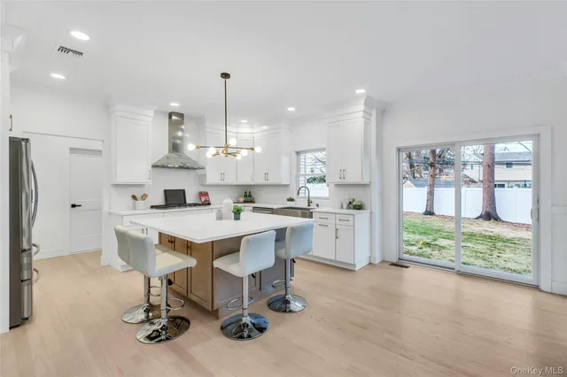a kitchen with stainless steel appliances kitchen island granite countertop a table chairs refrigerator and wooden floor