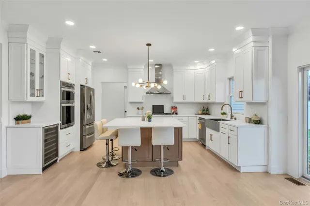 a large white kitchen with lots of counter space dining table and stainless steel appliances