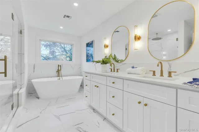 a spacious bathroom with a double vanity sink a mirror a bathtub and window