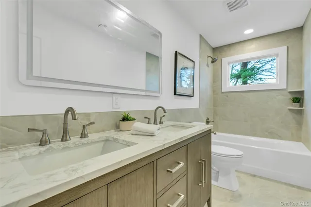 a bathroom with a granite countertop sink toilet and painting on the wall