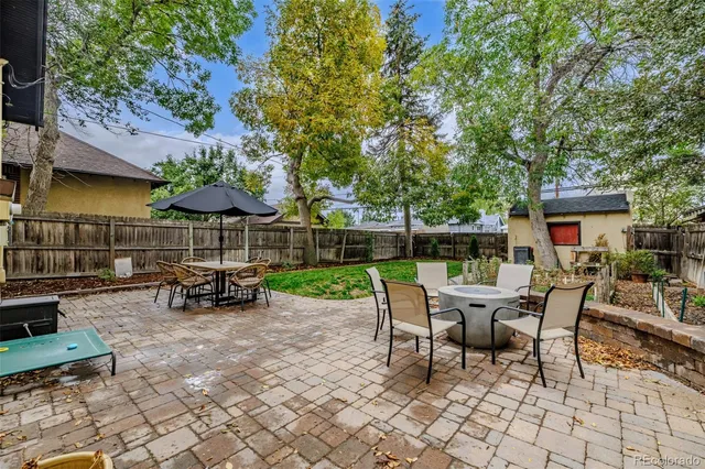 a view of a patio with table and chairs potted plants and a large tree