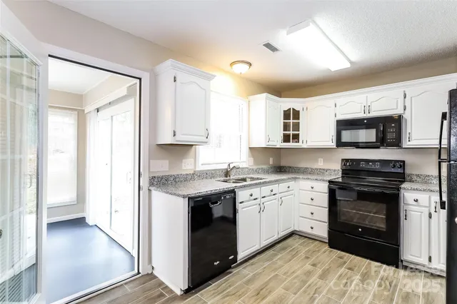 a kitchen with stainless steel appliances granite countertop a stove top oven a sink dishwasher and a refrigerator with wooden floor