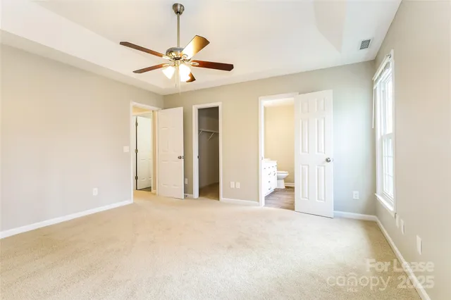 a view of a livingroom with a ceiling fan & windows
