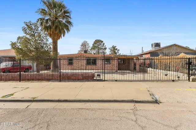 a view of a white house with a small yard and large trees