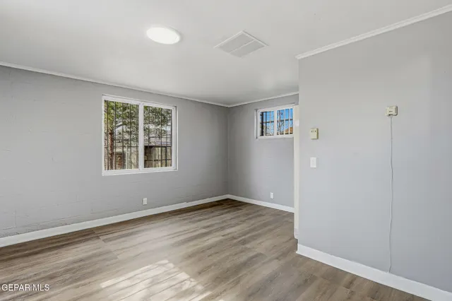 an empty room with wooden floor and windows