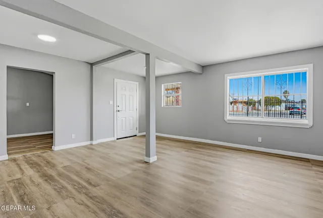 a view of an empty room with wooden floor and window