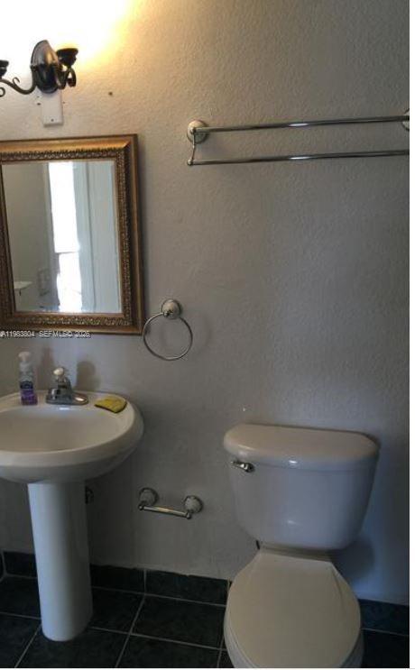 4705 Northwest 7th Street, Unit 2057 Miami, FL 33126 - Photo 8 of 9 a bathroom with a toilet sink and mirror