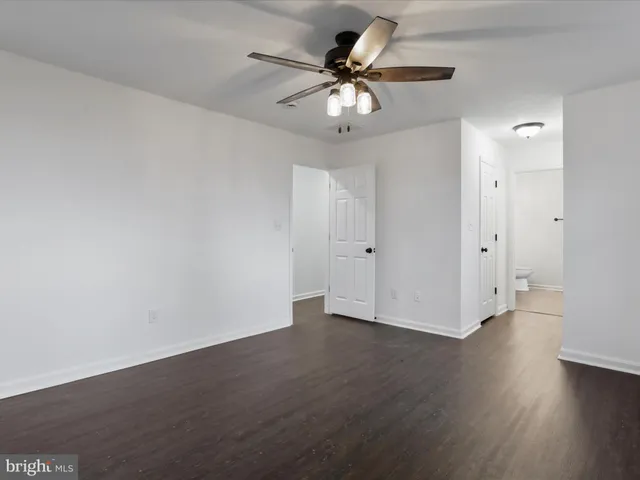 an empty room with wooden floor and ceiling fan