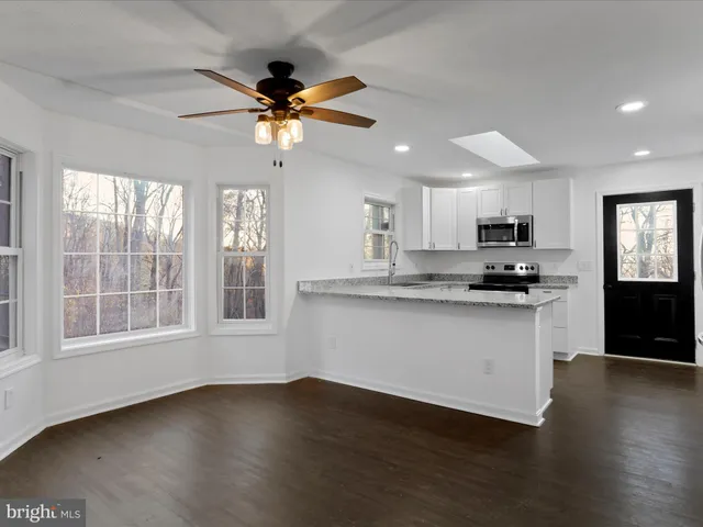 a kitchen with granite countertop a stove a sink a refrigerator a window and a counter space