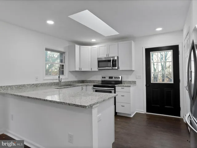 a kitchen with stainless steel appliances granite countertop a sink a stove a refrigerator cabinets and a window