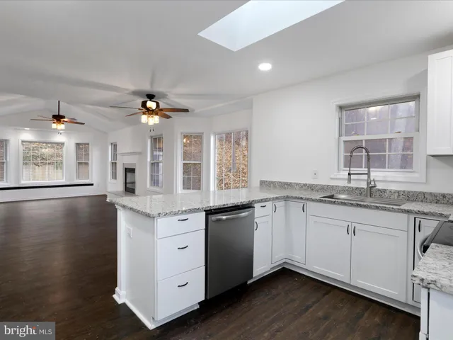 a kitchen with granite countertop a sink cabinets and wooden floor