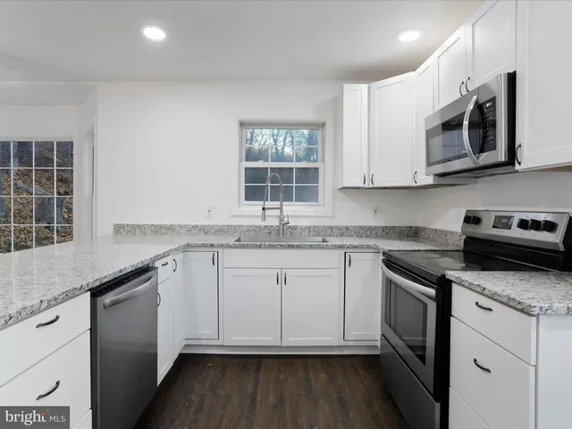 a kitchen with stainless steel appliances granite countertop white cabinets granite counter tops and a window