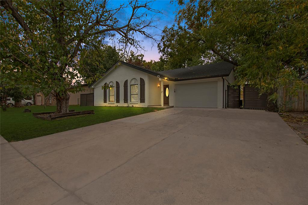 a front view of a house with a garden and trees