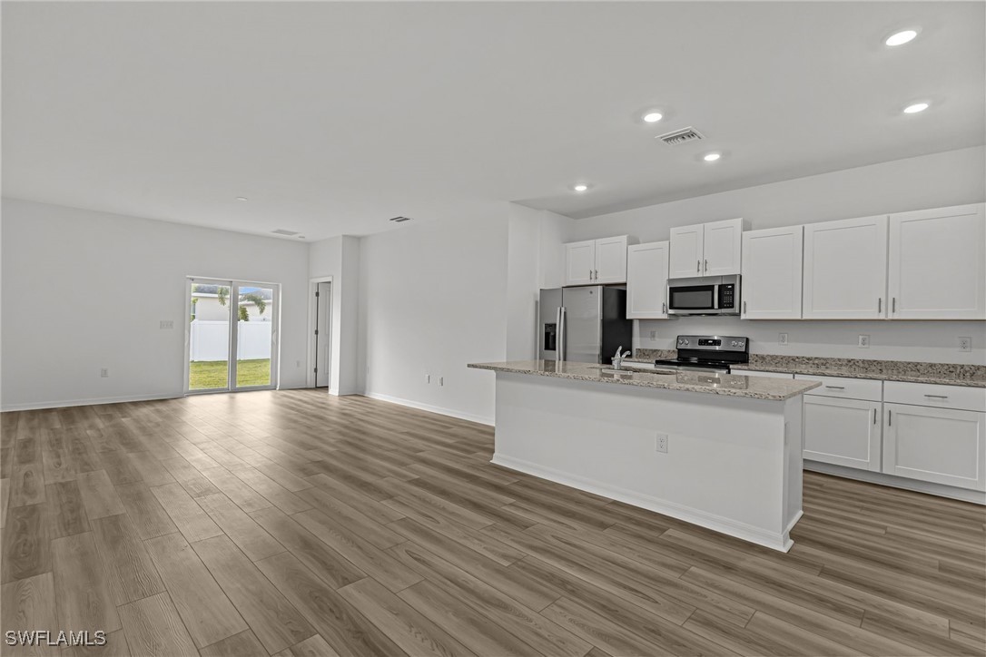 43153 Wild Indigo Road, Unit DOGWOOD Babcock Ranch, FL 33982 - Photo 3 of 20 a kitchen with stainless steel appliances granite countertop a stove a sink a refrigerator white cabinets and wooden floor