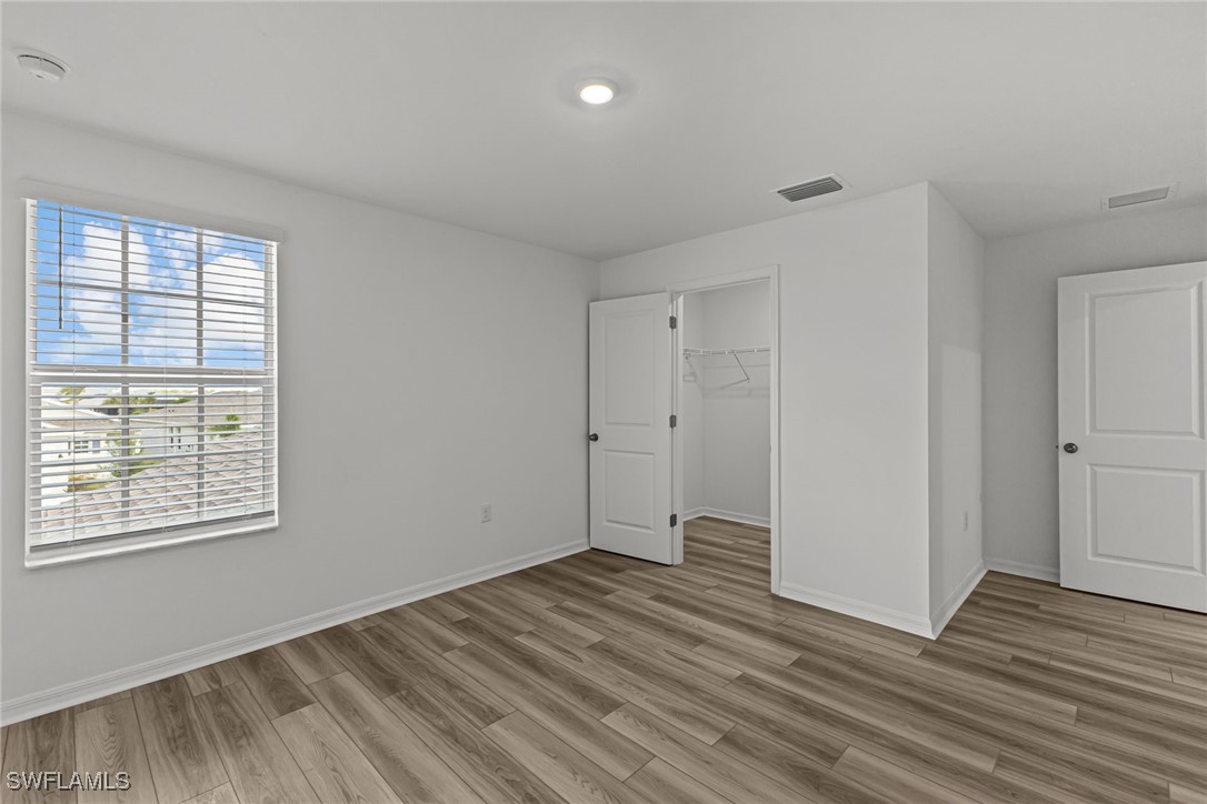 43153 Wild Indigo Road, Unit DOGWOOD Babcock Ranch, FL 33982 - Photo 8 of 20 a view of an empty room with wooden floor and a window