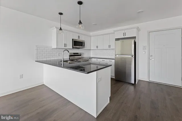 a kitchen with stainless steel appliances granite countertop a refrigerator a stove a microwave oven a sink and dishwasher with wooden floor