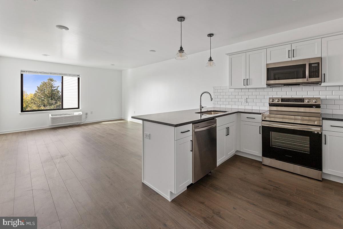 404 Fountain Street, Unit 406 Philadelphia, PA 19128 - Photo 3 of 10 a kitchen with stainless steel appliances granite countertop a stove a sink and a microwave