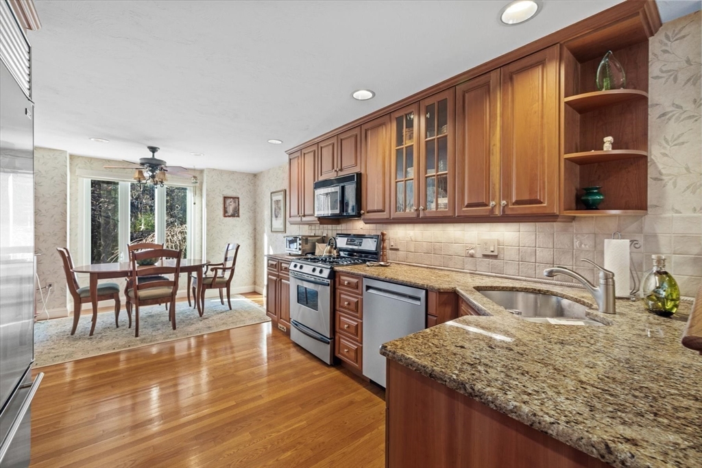55 Bay Farm Road, Unit 55 Duxbury, MA 02332 - Photo 11 of 37 a kitchen with stainless steel appliances granite countertop a stove top oven a sink dishwasher a dining table and chairs with wooden floor