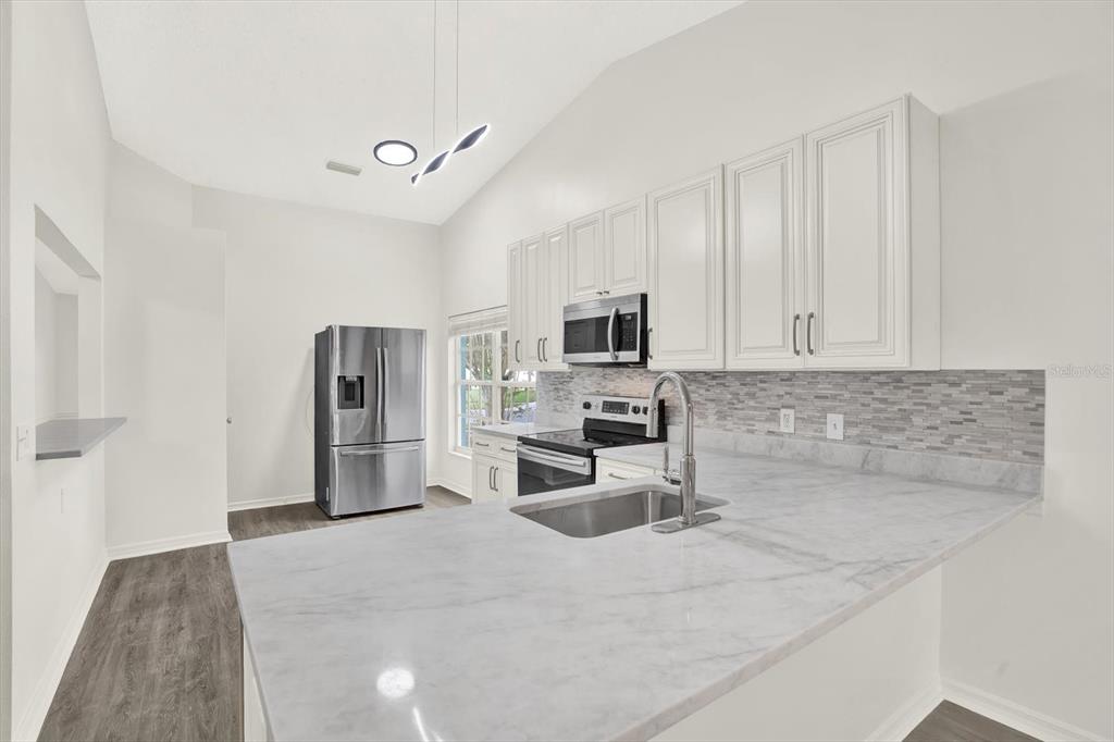 1712 Elk Spring Drive Brandon, FL 33511 - Photo 7 of 21 a kitchen with white cabinets and stainless steel appliances
