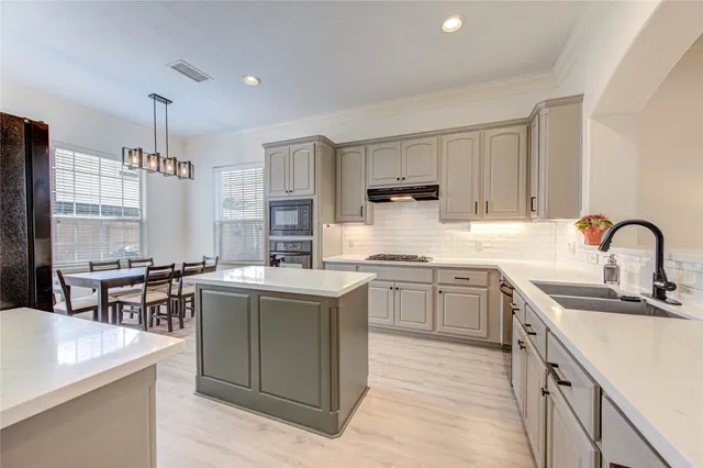 a kitchen with kitchen island granite countertop a sink stove top oven and refrigerator